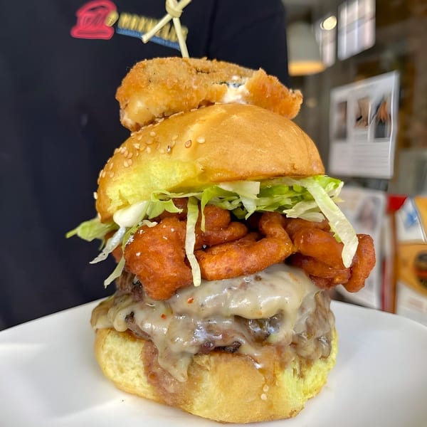 Maxwell's burger with melted cheese, crispy fried onions, lettuce, and a fried mozzarella stick.